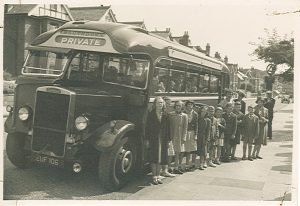 A group of children with learning disabilities standing next to a bus. This photo was taken in the 1950s. We think they were on an outing.